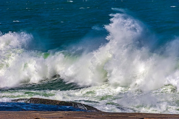 Fuertes olas chocando contra las rocas durante una tormenta en un día soleado