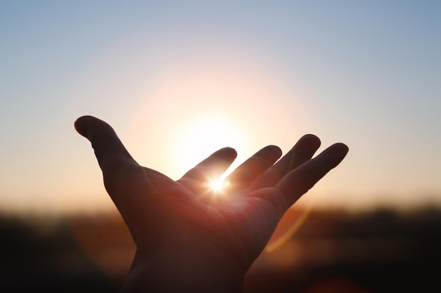 Fuertes rayos de luz brillando entre las manos extendidas hacia el sol naciente