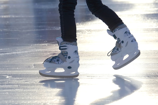 Füße auf den Schlittschuhen einer Person, die auf der Eisbahn rollt. Urlaubssport und Hobbys