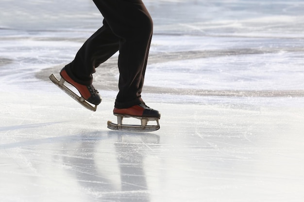 Füße auf den Schlittschuhen einer Person, die auf der Eisbahn rollt