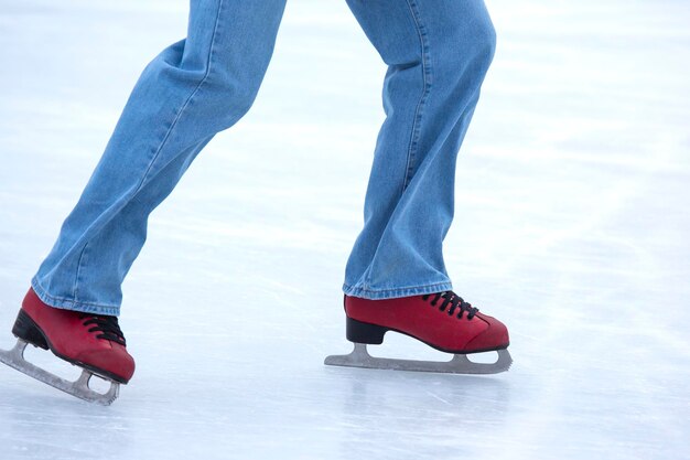 Füße auf den Schlittschuhen einer Person, die auf der Eisbahn rollt