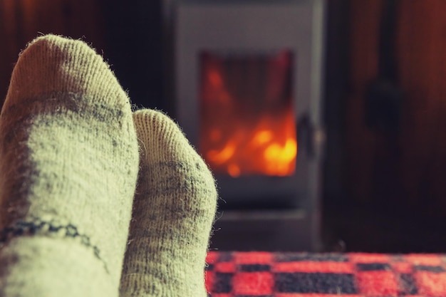 Füße Beine in Winterkleidung Wollsocken am Kamin Hintergrund Frau sitzt zu Hause im Winter oder au