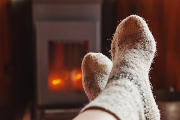 Füße Beine in Winterkleidung Wollsocken am Kamin Hintergrund Frau sitzt zu Hause im Winter oder au...