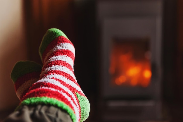 Füße Beine in Winterkleidung Wollsocken am Kamin Hintergrund Frau zu Hause am Winter oder Herbst Abend entspannen und aufwärmen Winter und kaltes Wetter Konzept Hygge Heiligabend