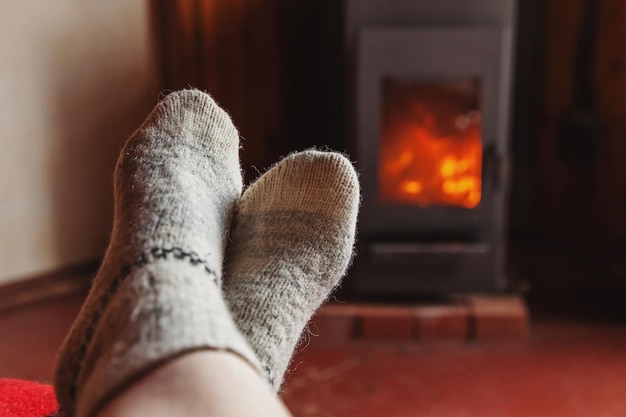 Füße Beine in Winterkleidung Wollsocken am Kamin Hintergrund Frau zu Hause am Winter oder Herbst Abend entspannen und aufwärmen Winter und kaltes Wetter Konzept Hygge Heiligabend