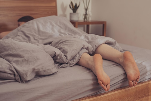 Füße einer Frau, die zu Hause im Bett schläft