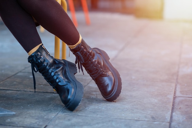 Füße einer Frau in schwarzen Schuhen auf der Stadtstraße an kalten Tagen