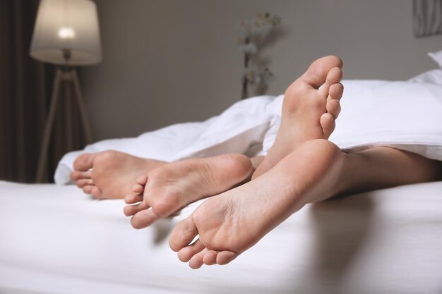 Füße eines Paares, das zu Hause Sex unter der Decke hat