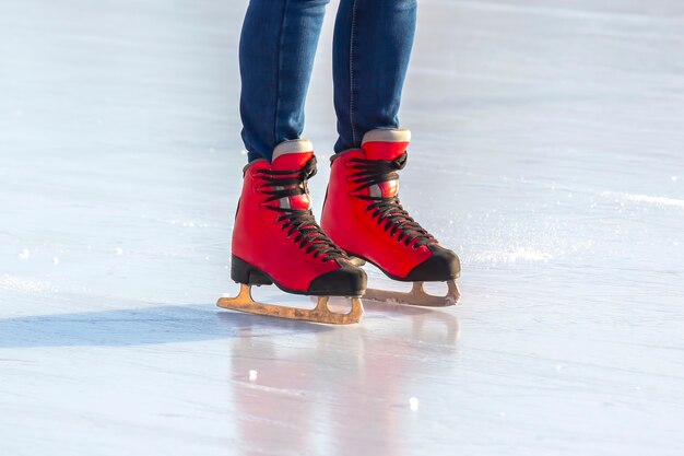 Füße in roten Schlittschuhen auf einer Eisbahn. Hobbys und Freizeit. Wintersport