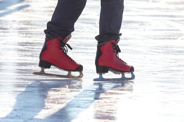 Füße in roten Schlittschuhen auf einer Eisbahn. Hobbys und Freizeit. Wintersport