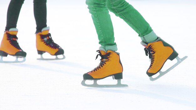 Füße in roten Schlittschuhen auf einer Eisbahn. Hobbys und Sport in den Winterferien