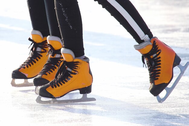 Füße in roten Schlittschuhen auf einer Eisbahn. Sport- und Winterurlaub