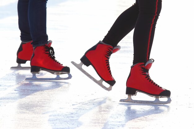 Füße in roten Schlittschuhen auf einer Eisbahn