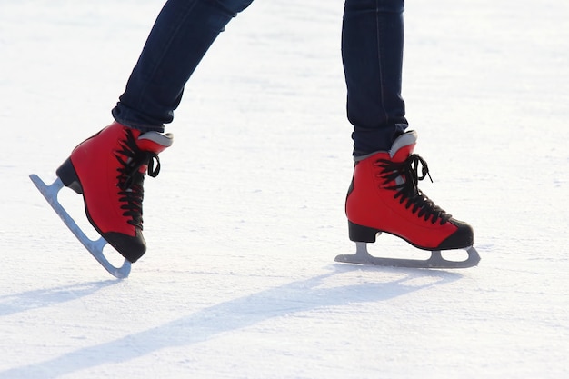 Füße in roten Schlittschuhen auf einer Eisbahn