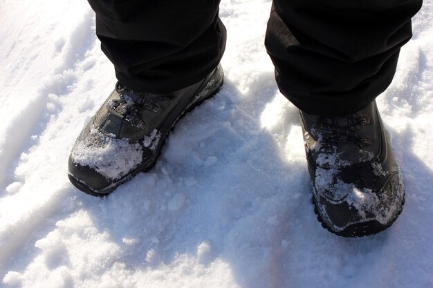 Füße in Stiefeln im Schnee. Draufsicht. Winterzeit.