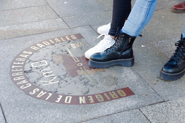 Füße junger Menschen stehen auf km 0 Zeichen von Madrid Spanien Konzepte des gemeinsamen Reisens Freundschaft
