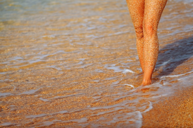 Füße Mädchen am Strand. Wellen laufen zum Ufer