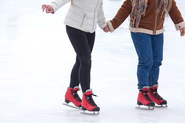 Füße verschiedener Leute, die auf der Eisbahn Schlittschuh laufen. Hobbys und Freizeit. Wintersport