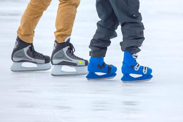 Füße verschiedener Leute, die auf der Eisbahn Schlittschuh laufen. Hobbys und Sport