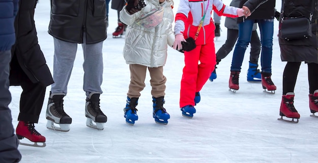 Füße verschiedener Leute, die auf der Eisbahn Schlittschuh laufen