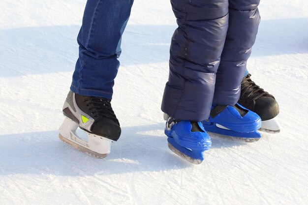 Füße verschiedener Leute, die auf der Eisbahn Schlittschuh laufen