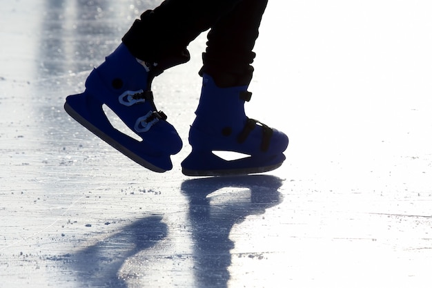 Füße von Menschen, die auf der Eisbahn Schlittschuh laufen