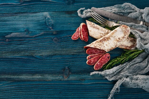 Foto fuet salami und rosmarin traditionelle spanische wurst auf blauem holzhintergrund draufsicht