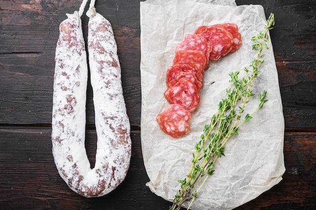 Fuet, Trockenwurst in Scheiben geschnitten auf altem Holztisch, Ansicht von oben.