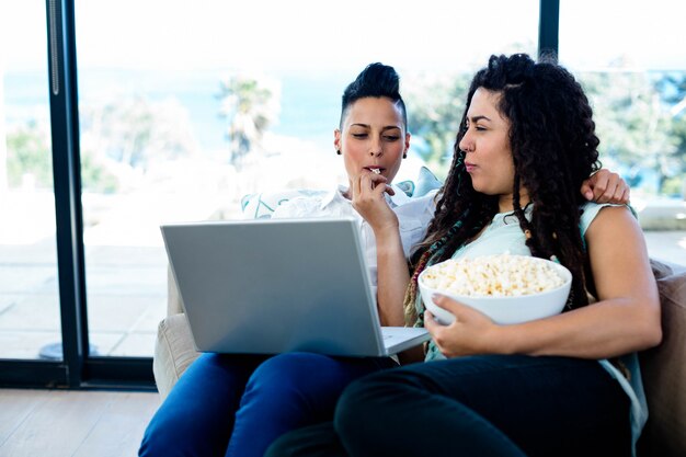 Fütterungspopcorn der Frau zu ihrem Partner bei der Anwendung des Laptops im Wohnzimmer