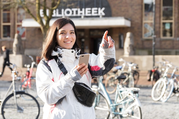 Fuja em uma cidade. Mulher jovem de etnia no início da primavera, usando um telefone para se orientar nas ruas.