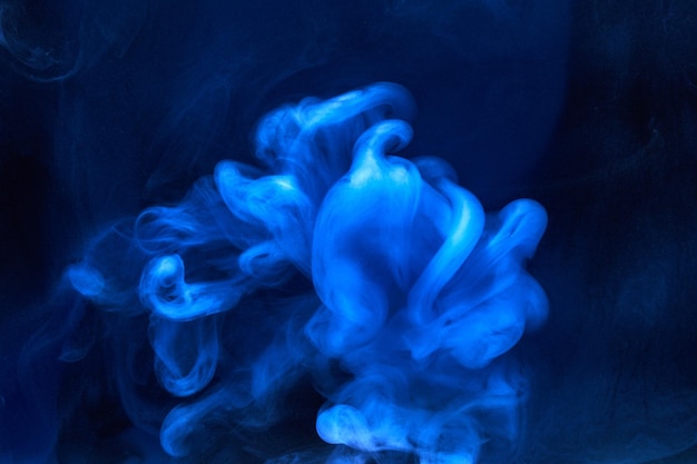 Fumaça azul sobre fundo de tinta preta, neblina colorida, mar oceânico em turbilhão abstrato, pigmento de tinta acrílica debaixo d'água