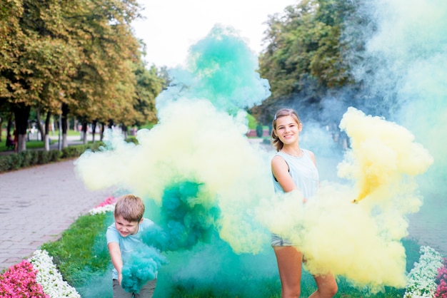 Fumaça colorida e crianças. fumaça de festa verde e amarela brilhante. aniversário ou festa. as crianças se divertem, riem e correm. feliz verão brilhante.