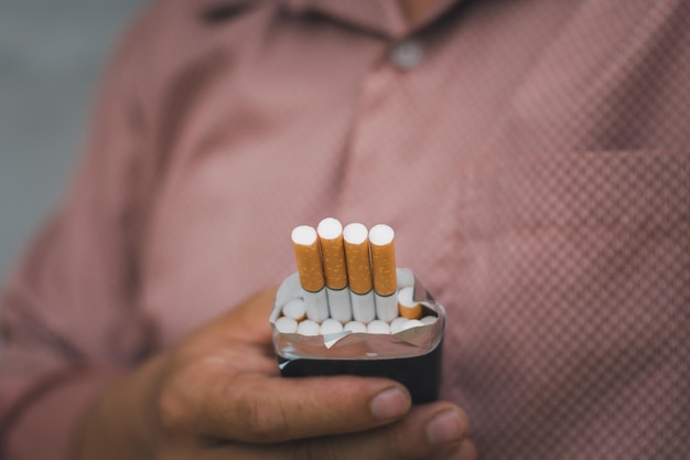 Un fumador que sostiene un paquete de cigarrillos abierto para que alguien lo traiga adicto y problema de salud concepto de problema de los pulmones espacio de copia para texto individual que se usa para contenido para adultos