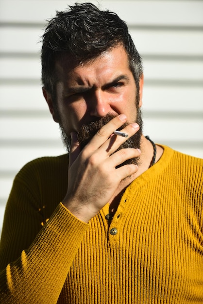 El fumador sostiene un cigarrillo en la boca Hombre con rostro serio
