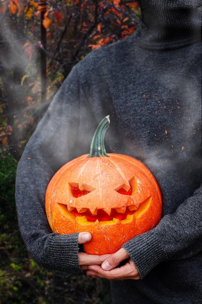 Fumar abóbora nas mãos das mulheres. Grande símbolo de halloween assustador. Foco seletivo