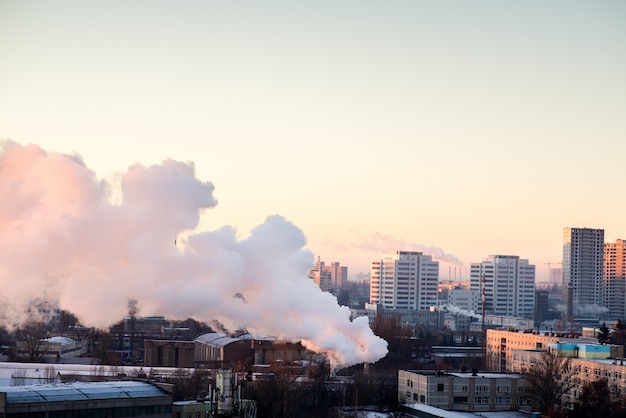 Fumar las chimeneas industriales al amanecer. Concepto para la protección del medio ambiente