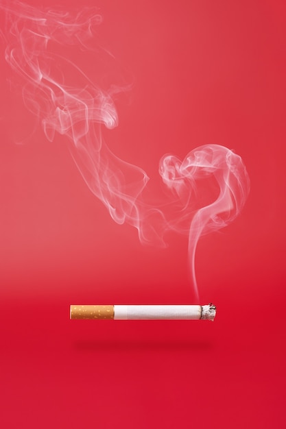 Fumar como signo de interrogación y fumar un cigarrillo sobre fondo rojo.