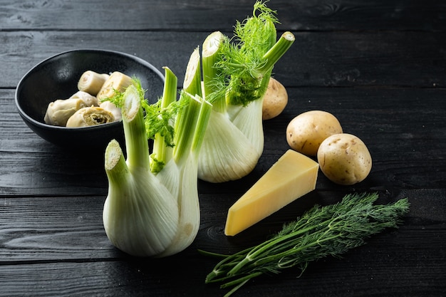 Funcho e alcachofra com ingredientes crus de parmesão, em mesa de madeira preta