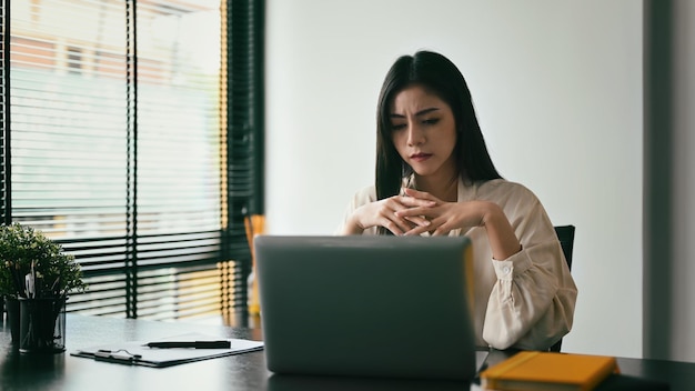 Funcionária frustrada olhando para laptop com problemas on-line ou notificação por e-mail