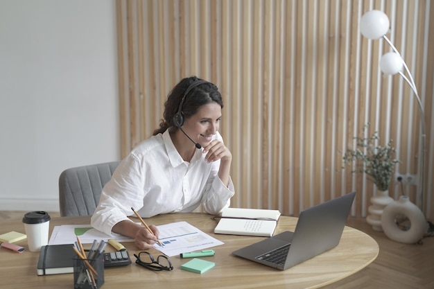 Funcionária italiana sorridente usando fone de ouvido sem fio participando de reunião on-line com colegas