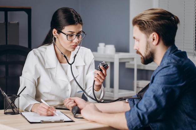 Foto funcionária médica medindo a pressão arterial do paciente