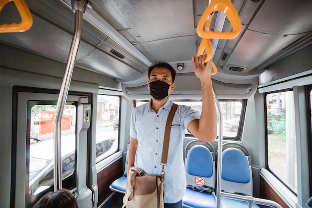 Funcionário asiático usando máscara para proteção em transporte público de passageiros em bonde