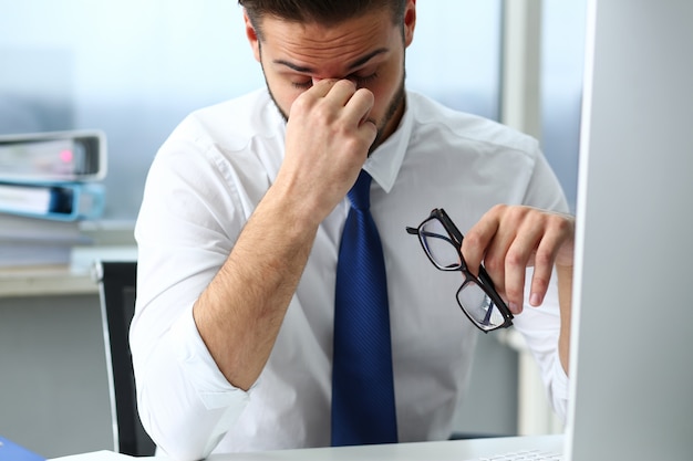 Funcionário cansado no local de trabalho do pc portátil usando óculos