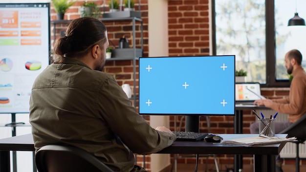 Funcionário corporativo usando tela verde no computador, trabalhando como freelancer com modelo de copyspace. Olhando para o fundo de maquete em branco com monitor de chroma key isolado na área de trabalho.