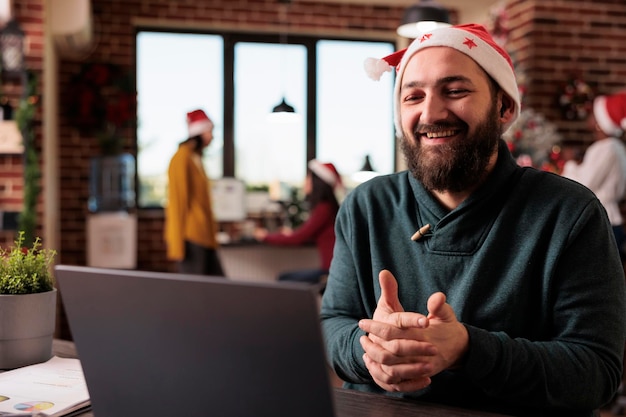 Funcionário de inicialização usando reunião de videochamada on-line no trabalho, sentado no escritório decorado com enfeites de natal e árvore. Pessoa falando no bate-papo por videoconferência remota, discussão por teleconferência.