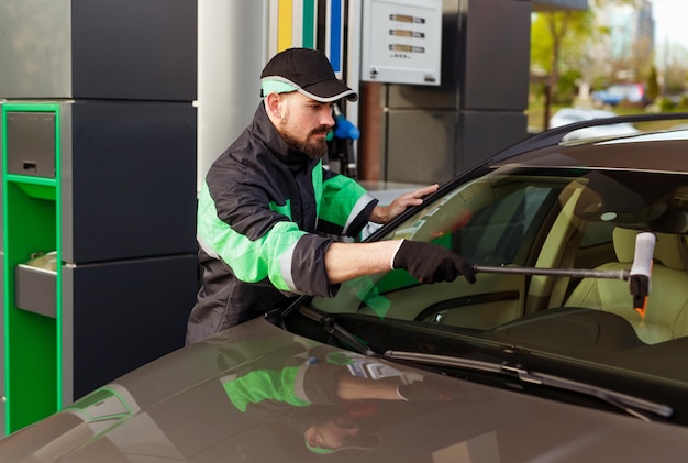 Funcionário do posto de gasolina lavando o para-brisa