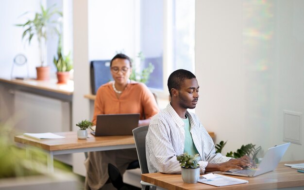 Foto funcionário do sexo masculino se acostumando com seu novo trabalho de escritório enquanto trabalha no laptop na mesa