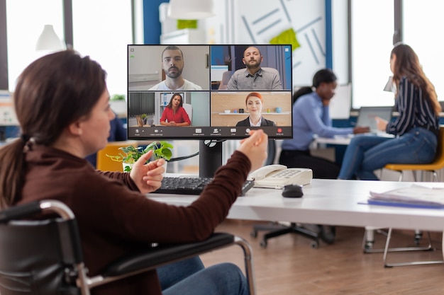 Foto funcionário inválido paralisado com deficiência durante reunião virtual falando em videochamada trabalhando no escritório de start up discutindo com parceiros online usando webcam