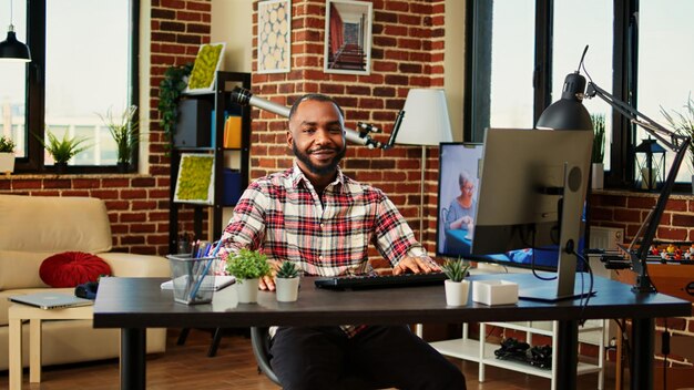 Foto funcionário remoto trabalhando em casa em um apartamento aconchegante e relaxante. alegre freelancer sorridente respondendo e-mails, digitando no teclado, teletrabalho em uma agradável sala de estar moderna