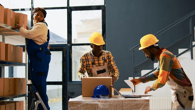 Funcionários afro-americanos organizando mercadorias em prateleiras e prateleiras, trabalhando na gestão de produtos. Trabalhadores da sala de armazenamento planejando remessa para distribuição de pedidos em lojas de varejo.